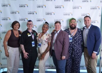 Six guests photographed together at a branded step-and-repeat backdrop in Orlando