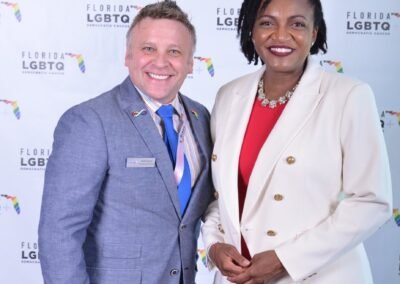 Two guests photographed together at a branded step-and-repeat backdrop in Orlando