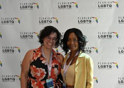 Two guests photographed together at a sponsor branded backdrop in Orlando