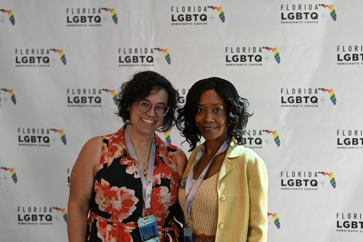 Two guests photographed together at a sponsor branded backdrop in Orlando