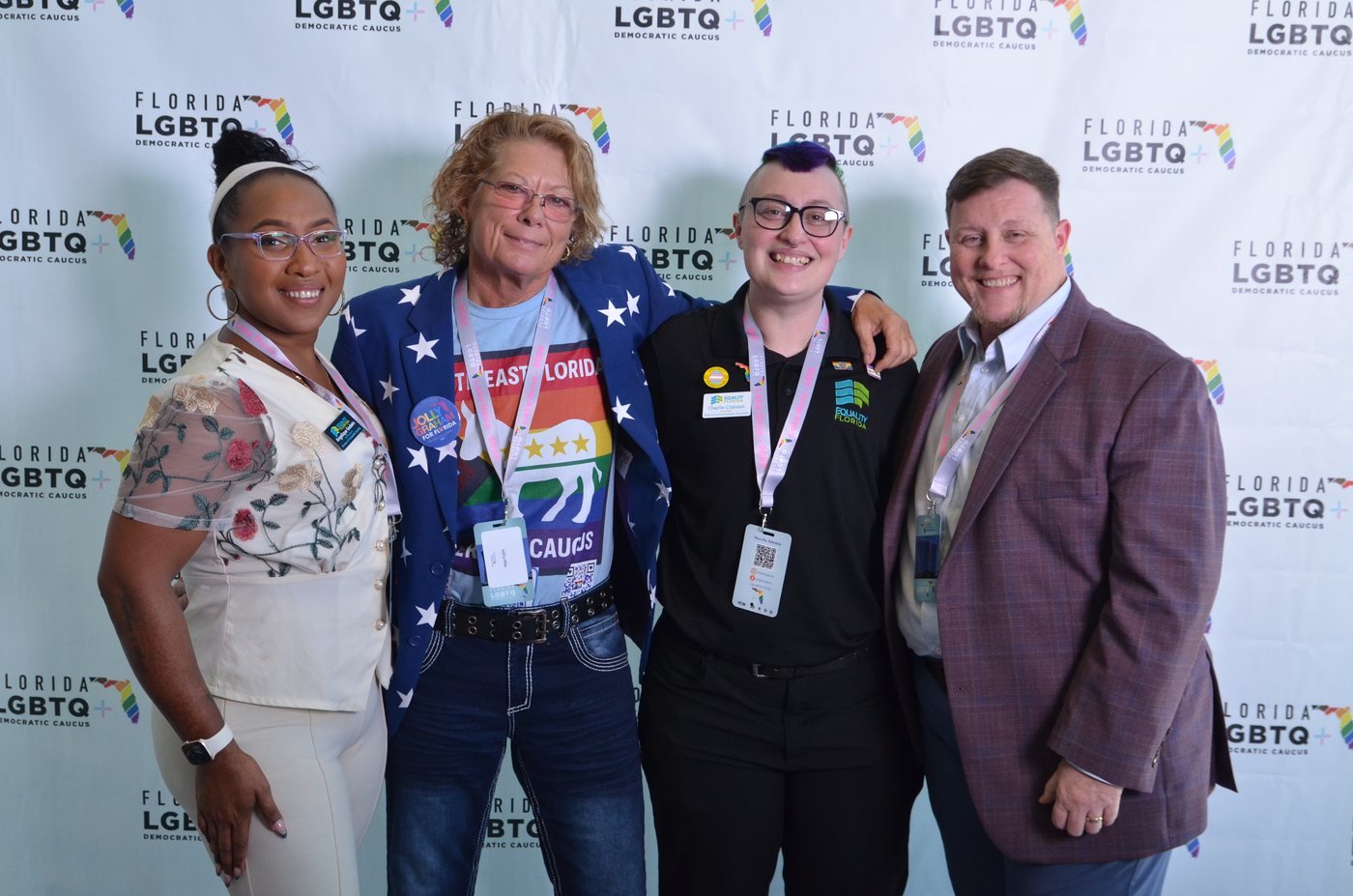 Four guests photographed together at a branded step-and-repeat backdrop in Orlando