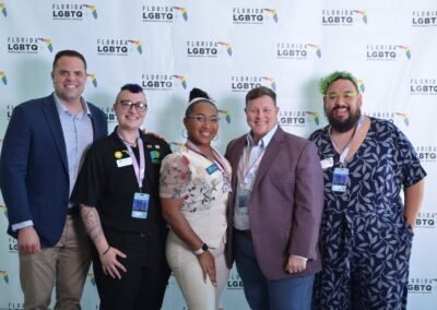Five guests photographed together at a branded step-and-repeat backdrop in Orlando
