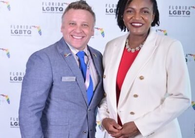 Two guests photographed together at a branded event backdrop