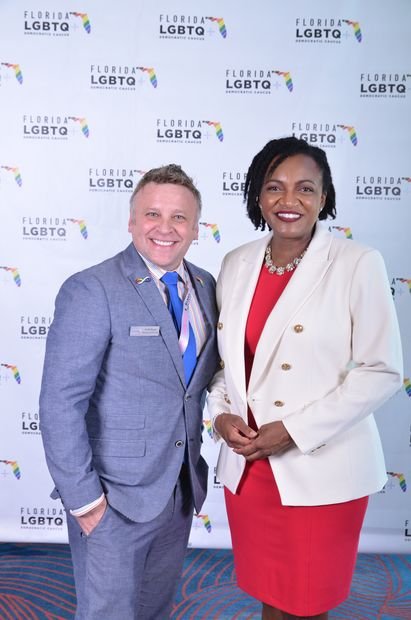 Two guests photographed together at a branded event backdrop