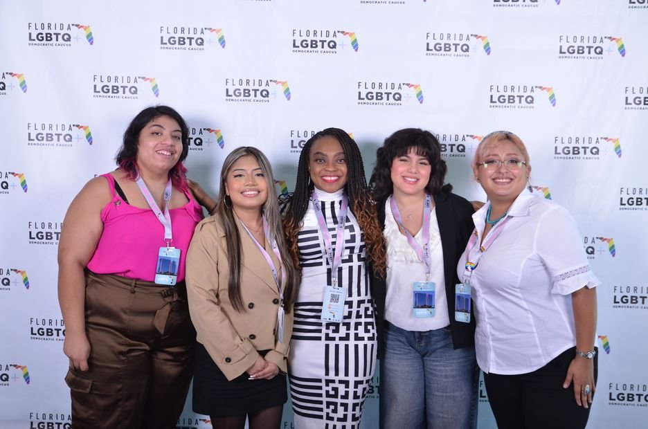 Five guests photographed as a group at a branded backdrop