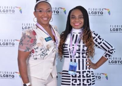 Two guests photographed together at a branded backdrop