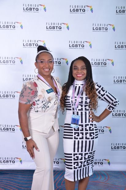 Two guests photographed together at a branded backdrop