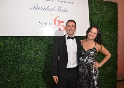 A couple in black tie photographed at a branded gala backdrop