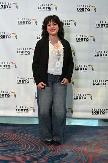 A guest photographed full length at a branded backdrop
