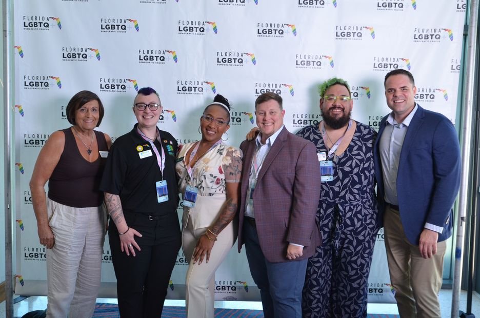 Six guests photographed together at a branded backdrop